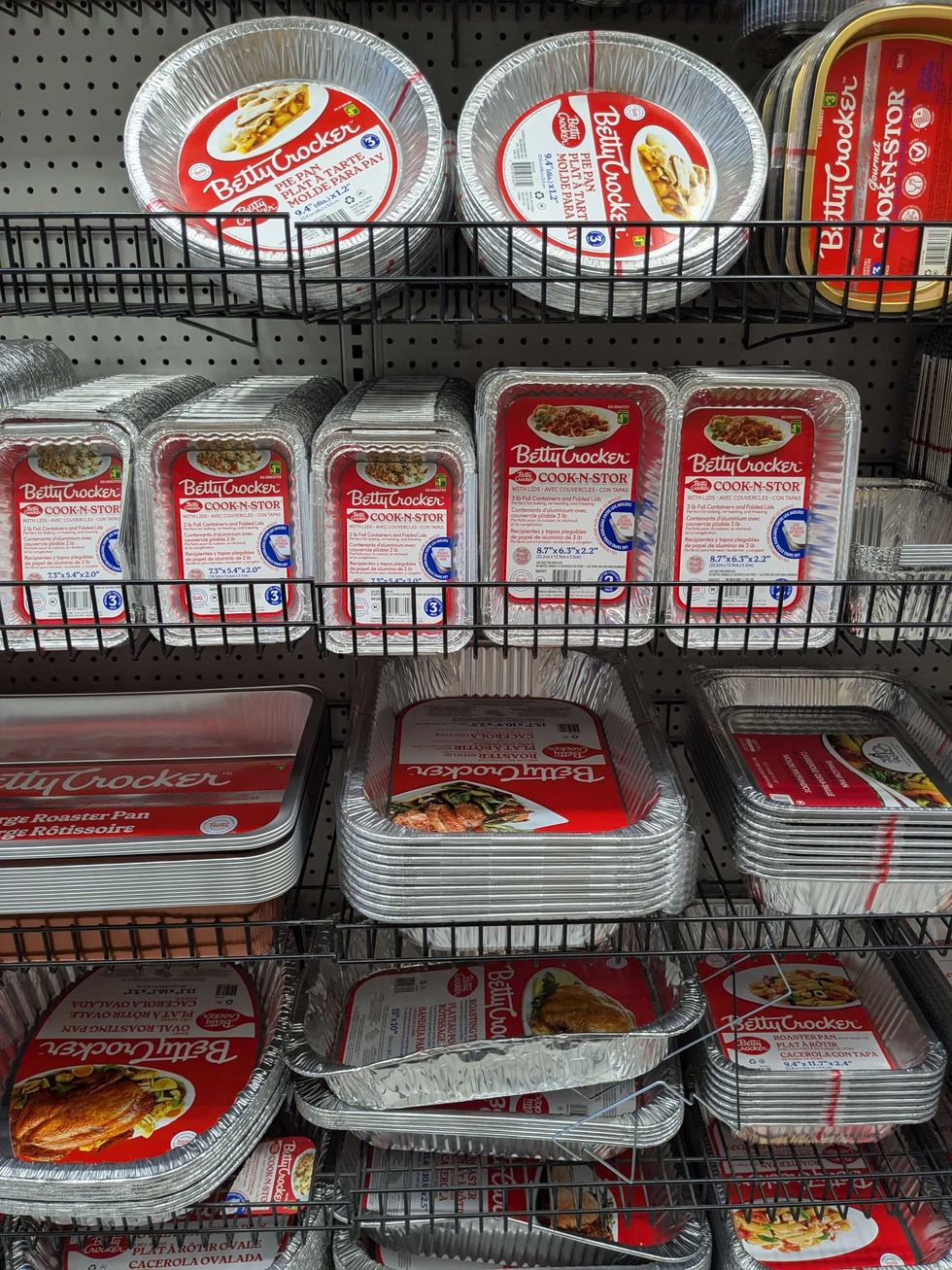 A shelf with various foil cookware pans and dishes