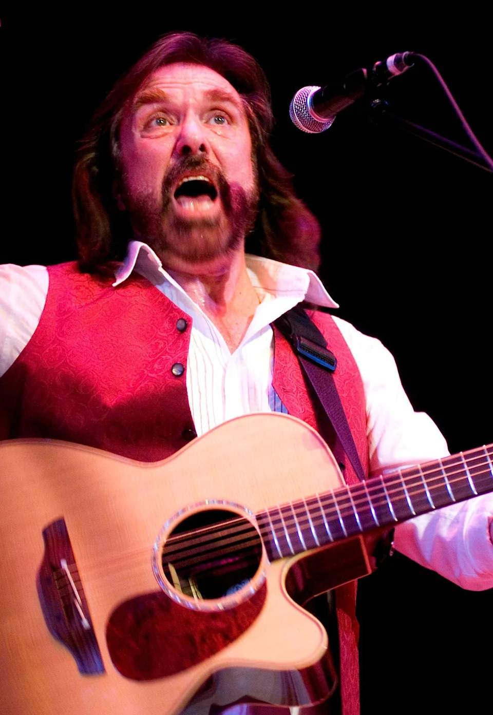 Dennis Locorriere singing and playing a guitar