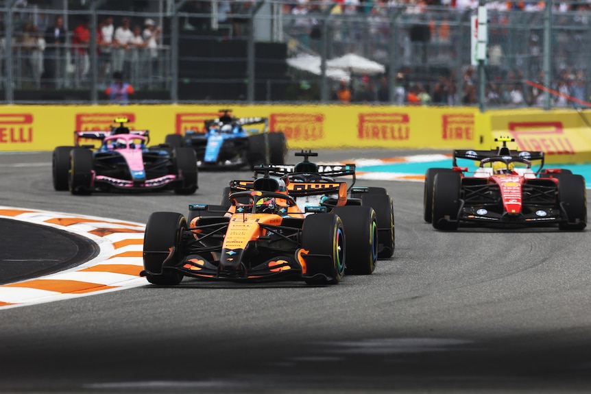 Five F1 cars racing close to each other during a grand prix