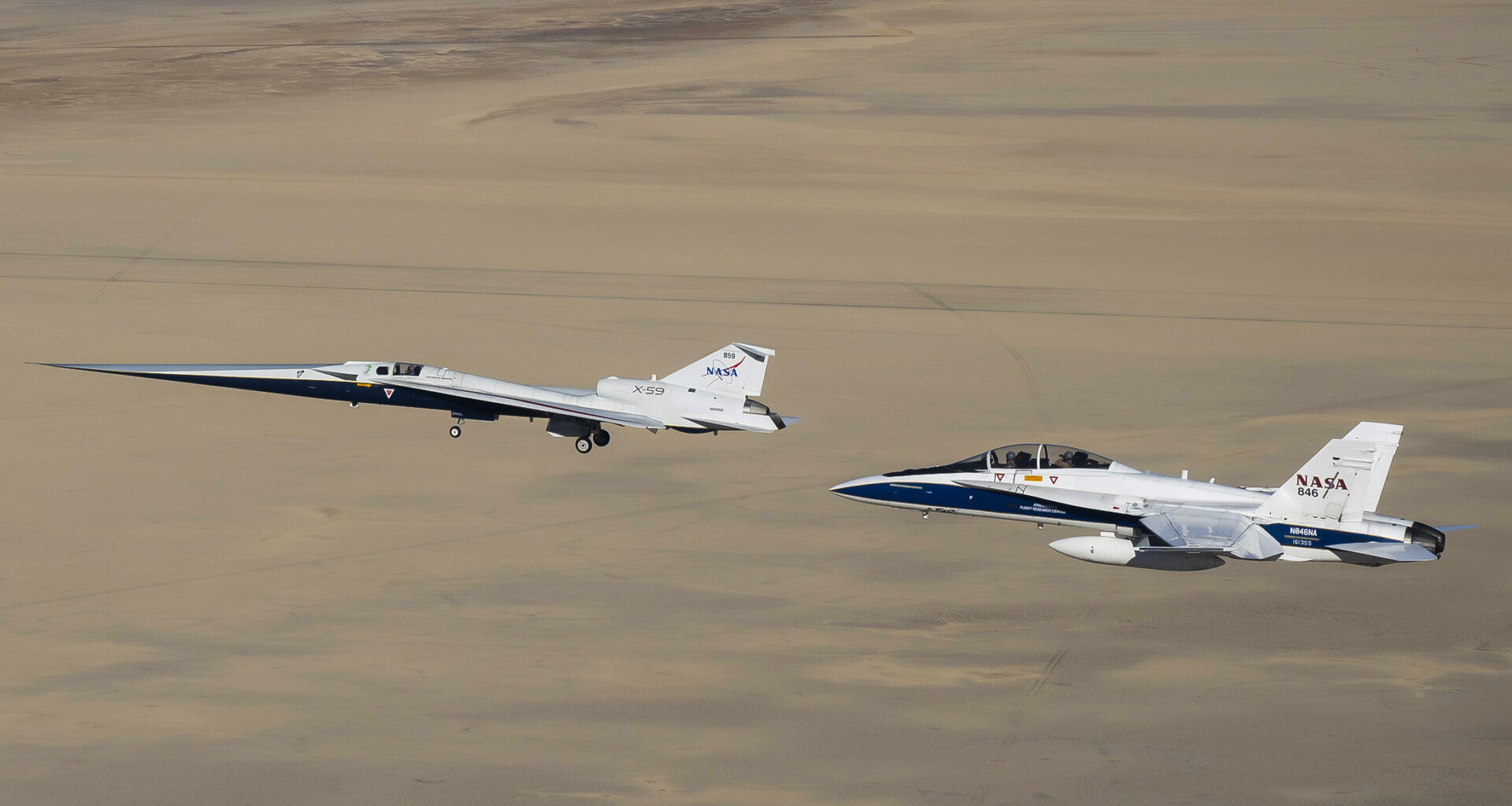 NASA’s X-59 flies above the Mojave Desert with a NASA F/A-18 chase aircraft nearby.
