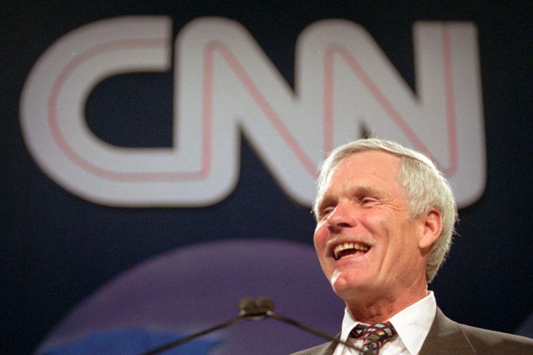 Ted Turner speaks at an event with the CNN logo in the background