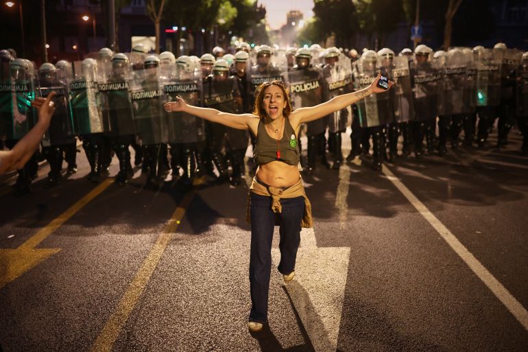 A woman who said she is pregnant walks in front of riot policemen as they prepare to disperse anti-government protesters during a rally led by Serbia's protesting university students who are pushing for major political changes in the Balkan country run by President Aleksandar Vucic, in Belgrade, Serbia, Saturday, May. 23, 2026. (AP Photo/Armin Durgut)