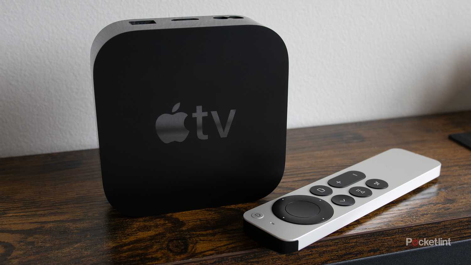 The Apple TV 4K sitting on a shelf with the Siri Remote