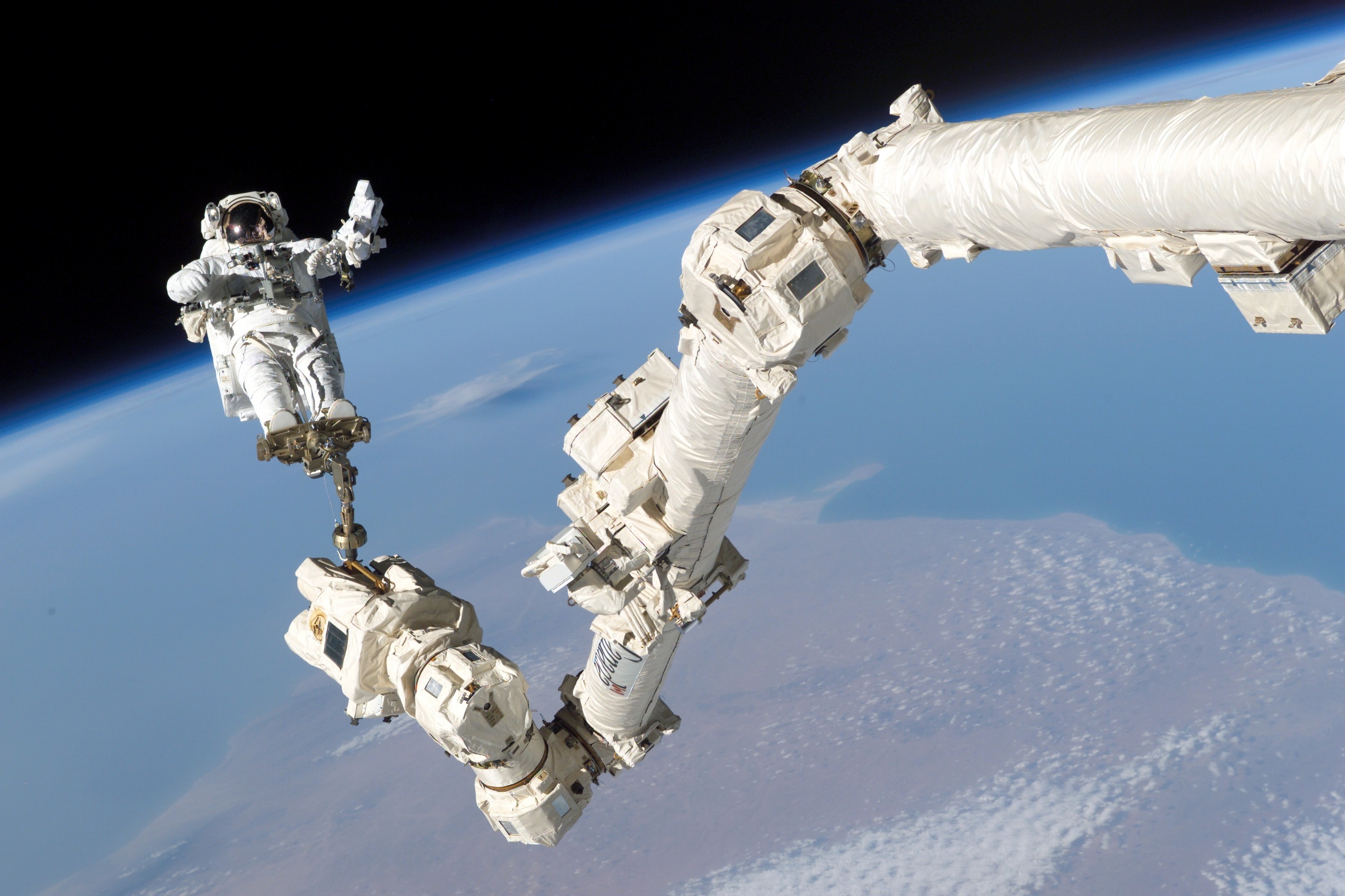 Astronaut Steve Robinson is shown in space clamped to the Canadarm2. 