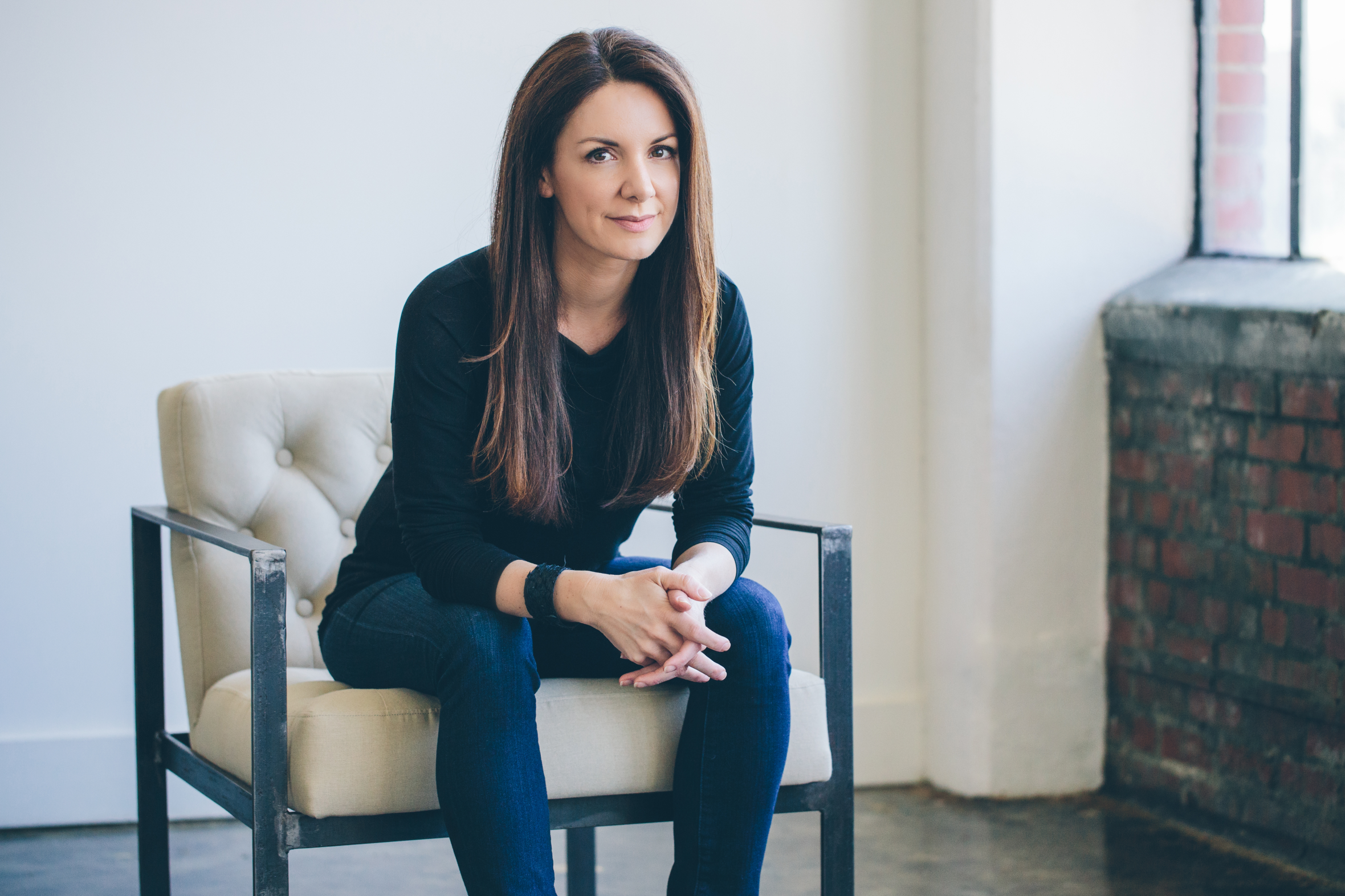 Kat Cole, CEO of AG1, seated in a white tufted chair, looking forward.