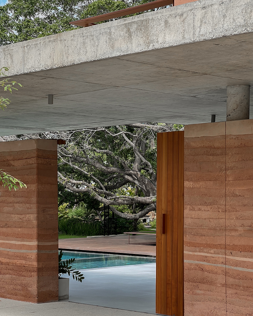 a pair of banyan trees anchors anonym studio’s open-air family house in thailand - 3