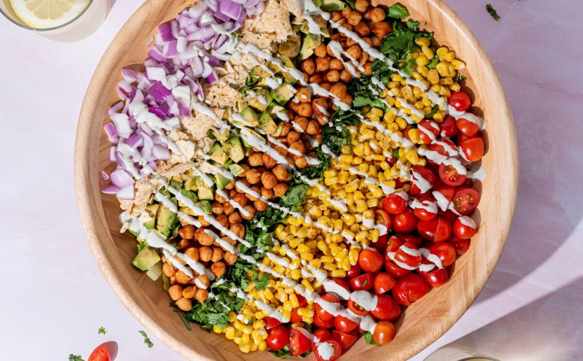 a picture of a beautifully assembled bbq chickpea chopped salad made with a rainbow of vegetables including tomato, corn, chickpeas, lettuce, corn chips, and a hempseed dressing for gluten-free lunch ideas