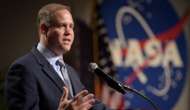 a white man in a suit talks into a microphone