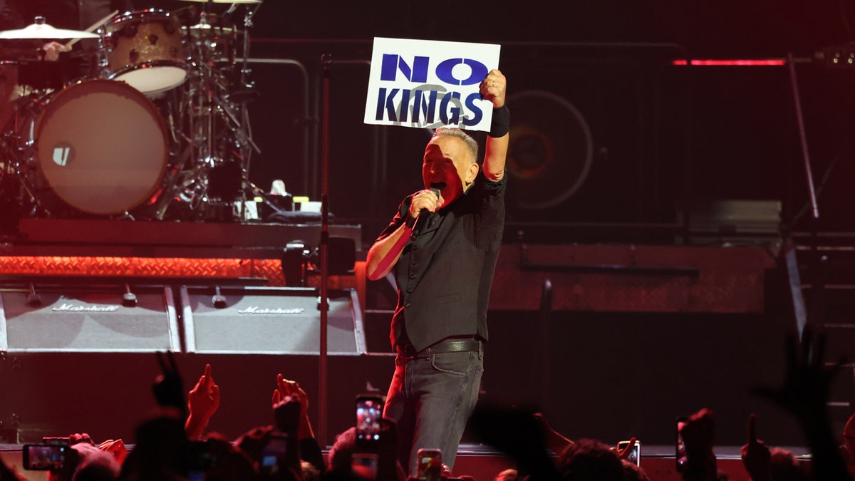 Bruce Springsteen holding a No Kings sign on stage