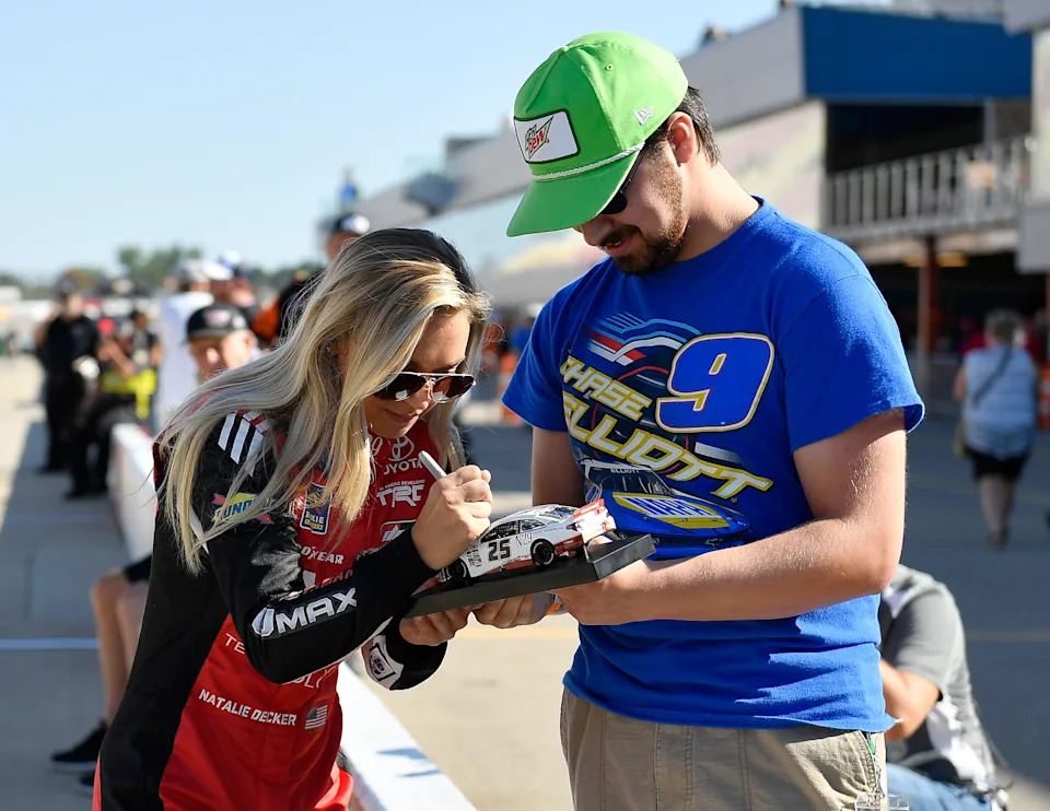 Natalie Decker, driver of the #54 N29 Technologies LLC Toyota, signs autographs during qualifying for the NASCAR Gander Outdoor Truck Series Corrigan Oil 200.