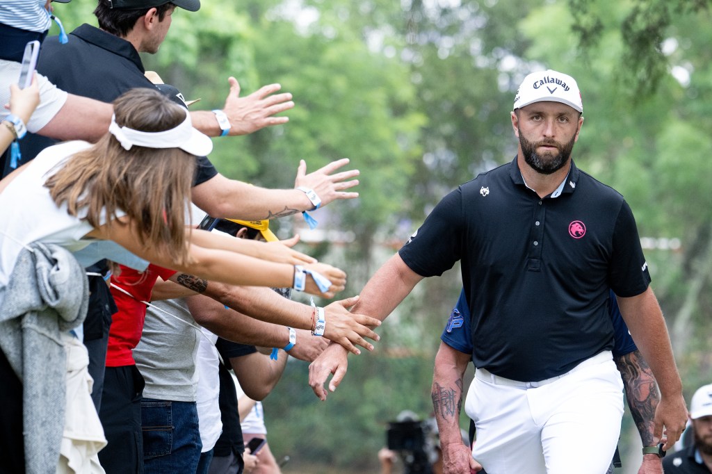 Golfer Jon Rahm high-fiving fans.