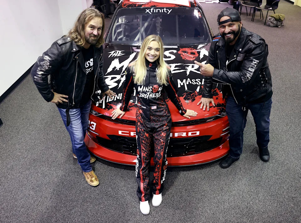 NASCAR Xfinity Series driver Natalie Decker poses for photos as she makes an appearance with actors Mike Carey and Chris Margetis.