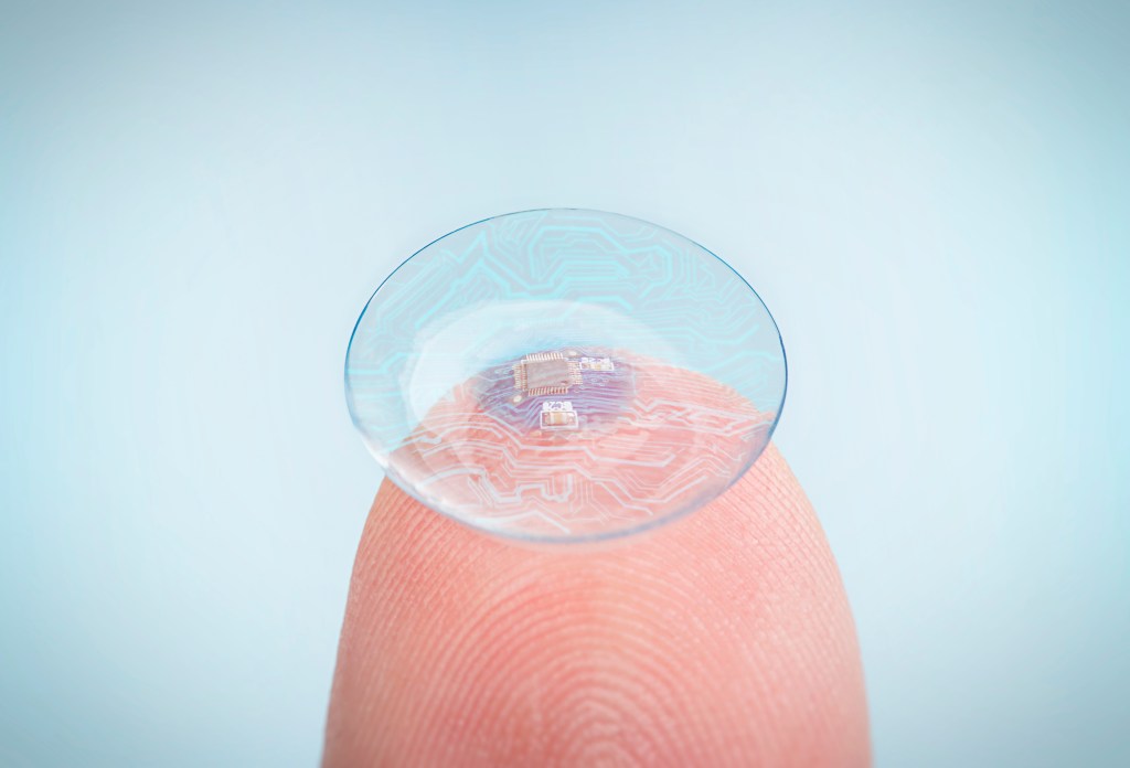 A futuristic contact lens with integrated digital and biometric implants resting on a fingertip.
