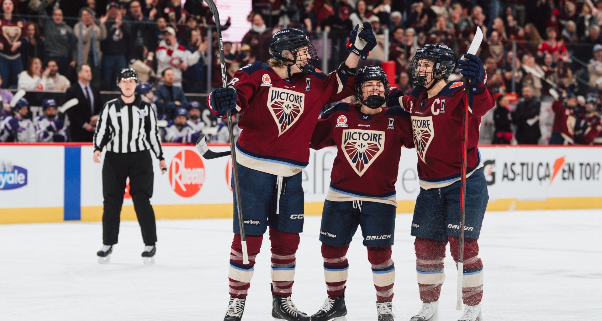 Three Victoire players celebrate on the ice.