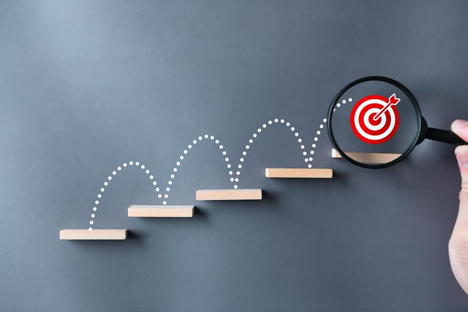 A bullseye jumping up stairs with a magnifying glass on it.
