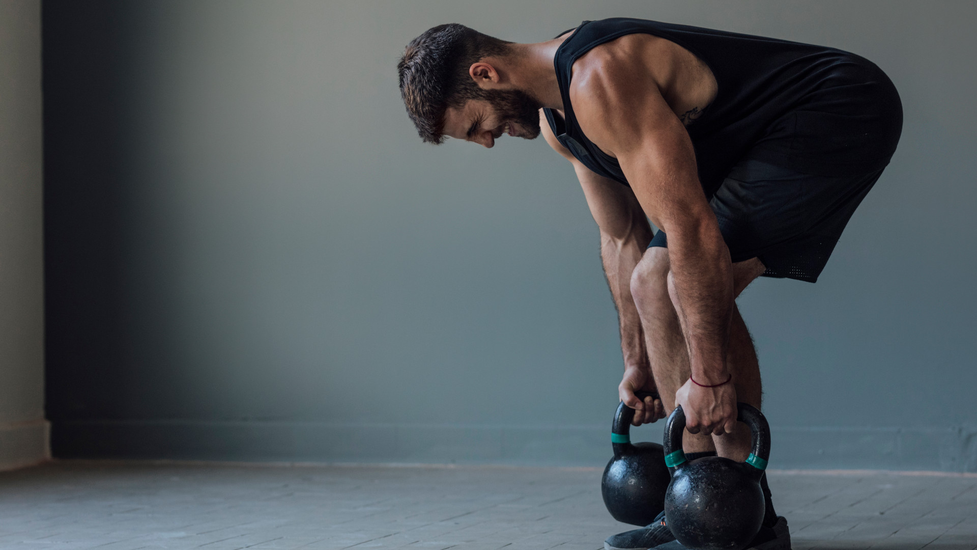 A man performing the gladiator deadlift with two kettlebells