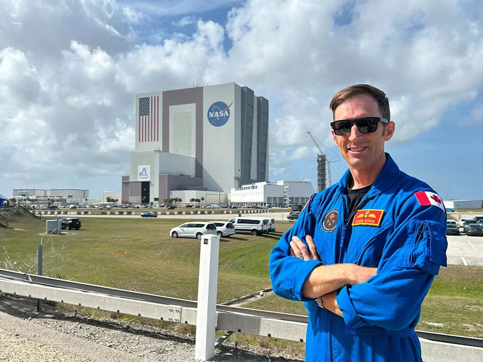 The Vehicle Assembly Building is seen in the distance as Canadian astronaut Joshua Kutryk poses for a portrait at NASA’s Kennedy Space Center in Florida on March 30, 2026.