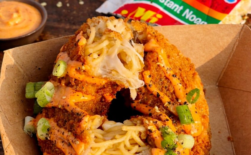 A savory donut-shaped ring made of ramen noodles with a cheesy center, deep-fried to a crisp and topped with tangy sauces.