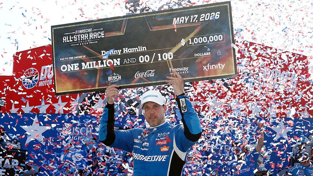Denny Hamlin holding a one million dollar check in victory lane at Dover Motor Speedway