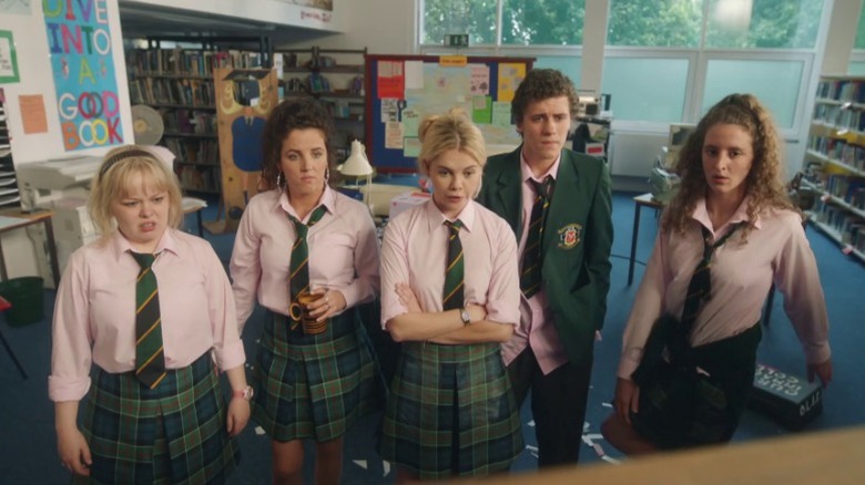Clare (Nicola Coughlan), Michelle (Jamie-Lee O'Donnell), Erin (Saoirse-Monica Jackson), James (Dylan Llewellyn), and Orla (Louisa Harland) looking at a blackboard on Derry Girls S1E6