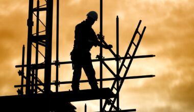 Silhouette of a construction worker on scaffolding, against a dramatic golden sky. The scene conveys industry and focus at dusk.