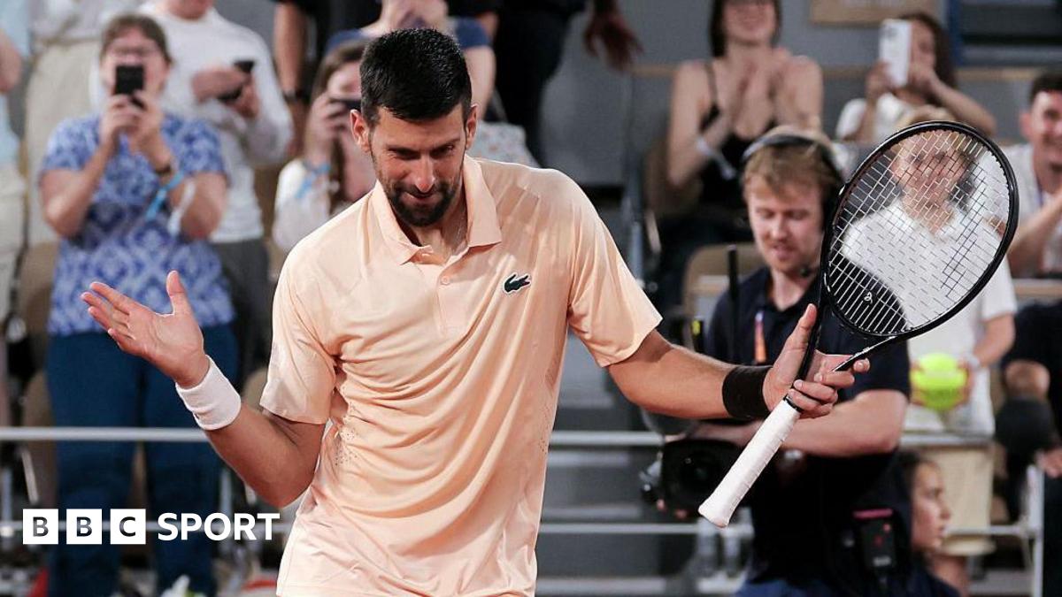 Novak Djokovic, wearing a peach polo shirt, dances with his racquet in his left hand