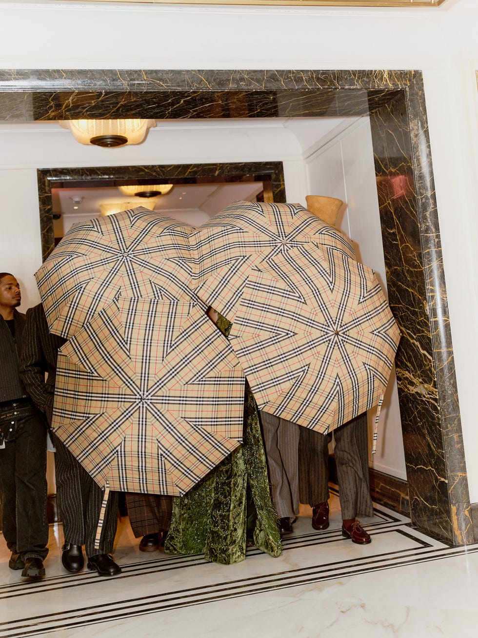 Group of individuals holding distinctive umbrellas in an entrance hall.
