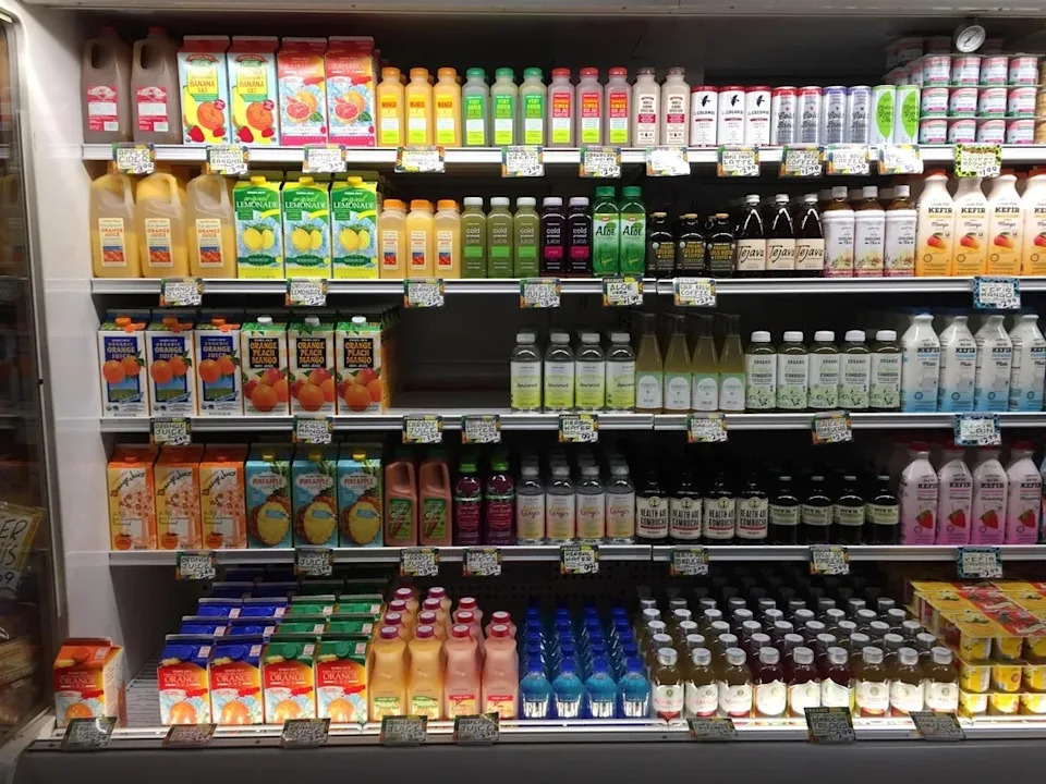 A grocery store shelf filled with various juice and beverage bottles, labeled with different flavors and brands