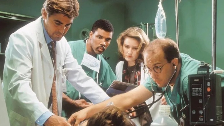 Doug Ross, Peter Benton, Susan Lewis, and Mark Greene standing over patient
