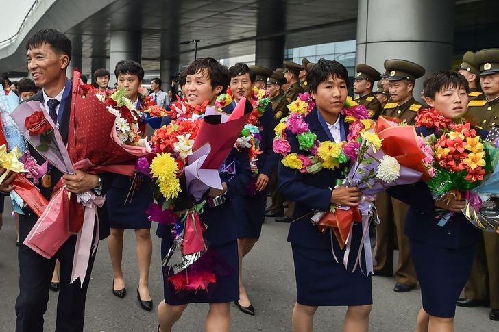 Members of North Korea's team and their coach Ji Yun-nam, left, who won the 2026 AFC U-17 Women's Asian Cup in China, are welcomed after their arrival at Pyongyang International Airport in Pyongyang, May 19. AFP-Yonhap