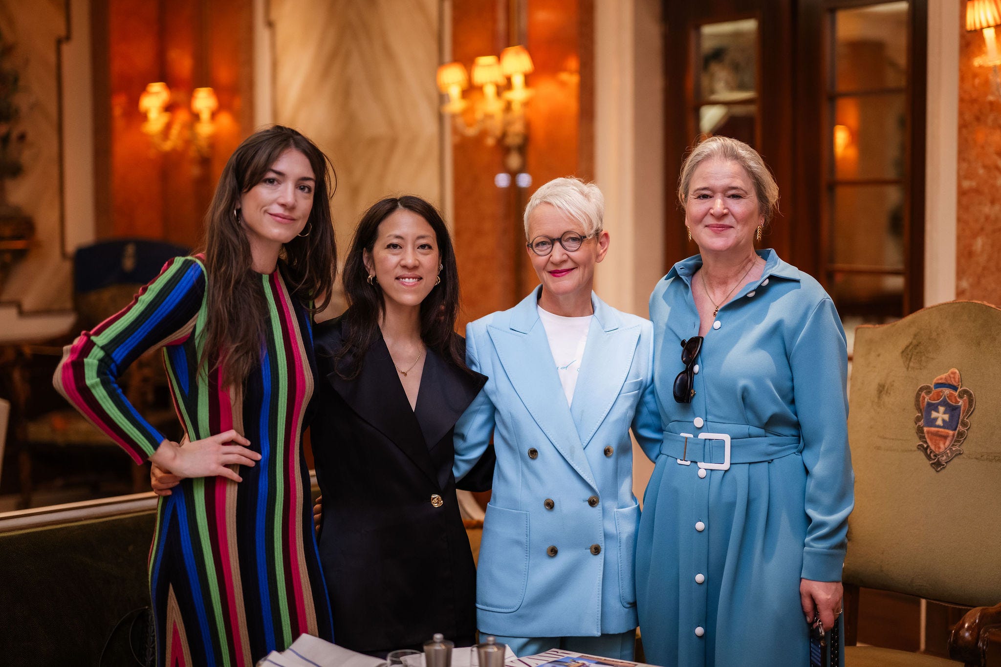 Group of four women posing together in a luxurious indoor setting