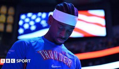 Shai Gilgeous-Alexander of Oklahoma City Thunder in a blue team leisurewear top and white headband, with his head bowed
