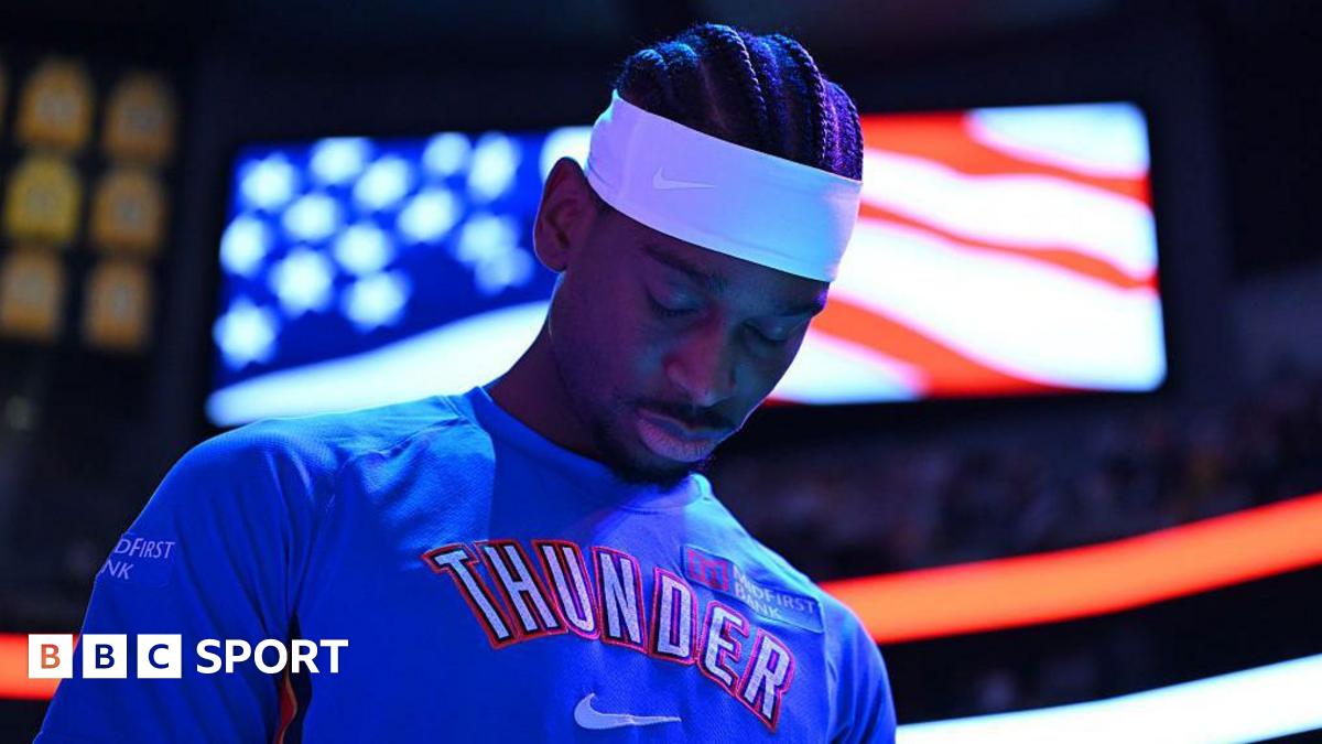 Shai Gilgeous-Alexander of Oklahoma City Thunder in a blue team leisurewear top and white headband, with his head bowed