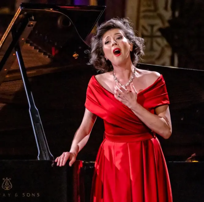 Lisette Oropesa performing in a red dress beside a grand piano.