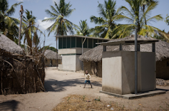 A double storey home next to some homes made of grass