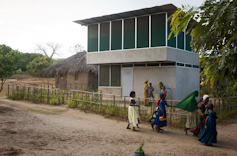 A double storey building made of concrete with wire mesh covering all windows to keep mosquitos out