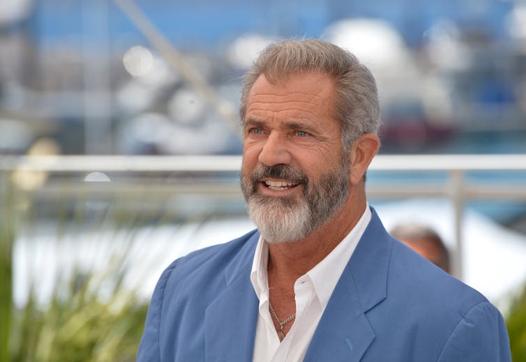 Actor Mel Gibson in a white shirt and blue blazer.