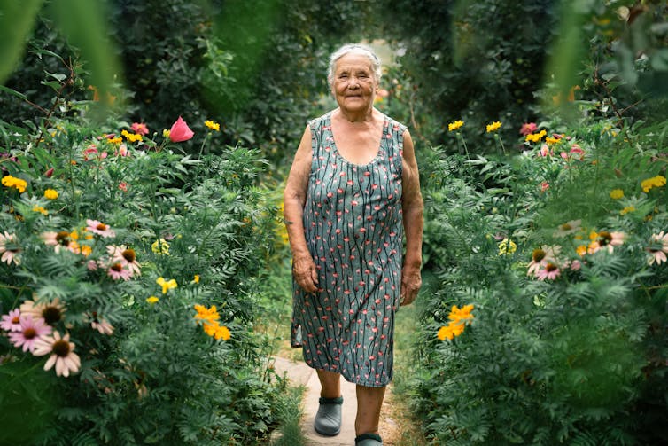 Older woman walking through wild garden flowers in summer