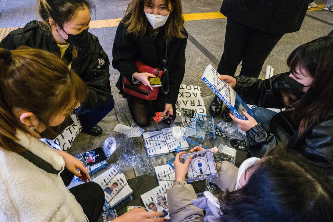 NCT fans gather at the entrance of a metro station to swap collectable cards featuring images of band members on December 15, 2021.