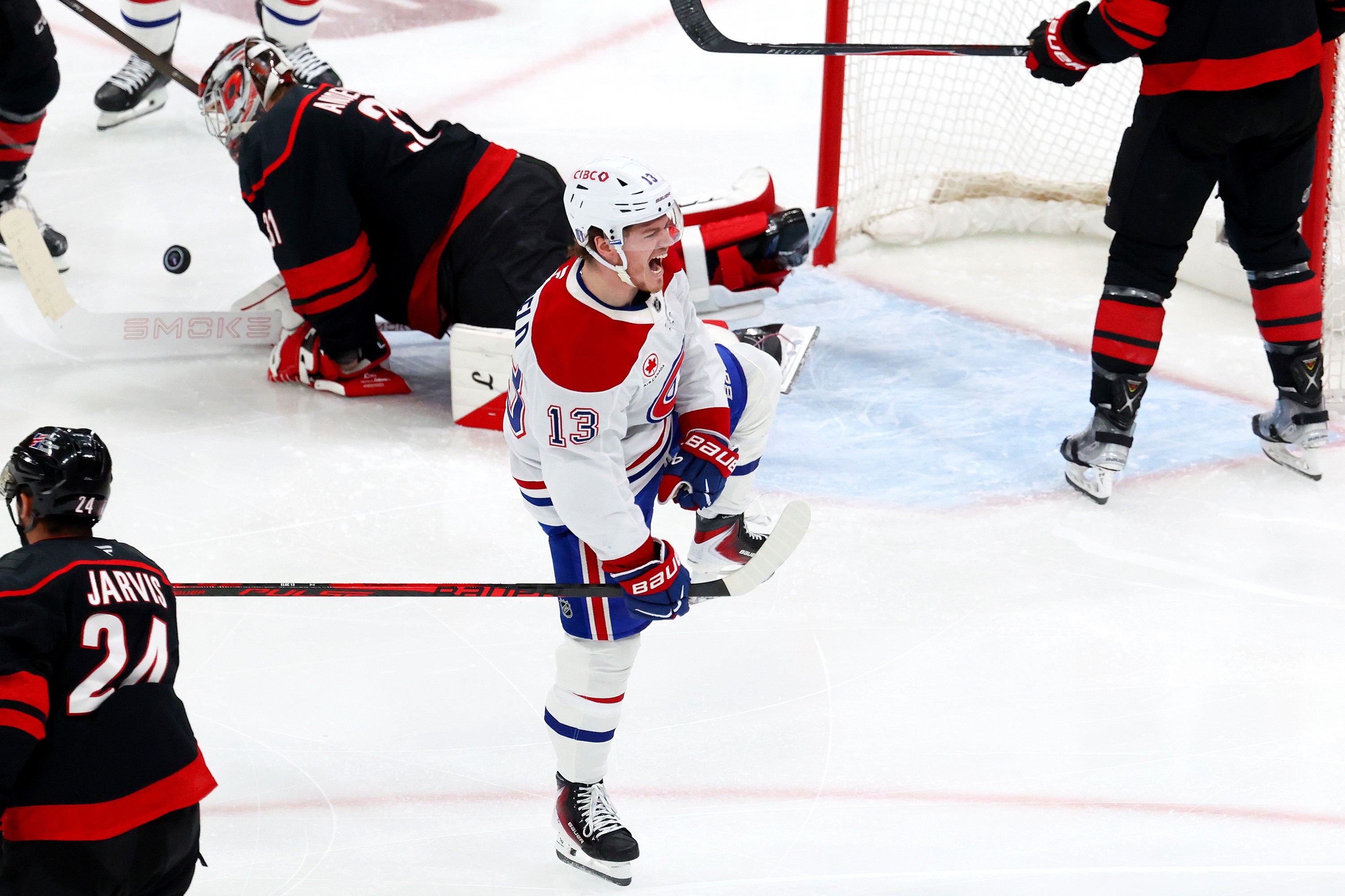 Hockey player celebrates in front of the net after scoring a goal.
