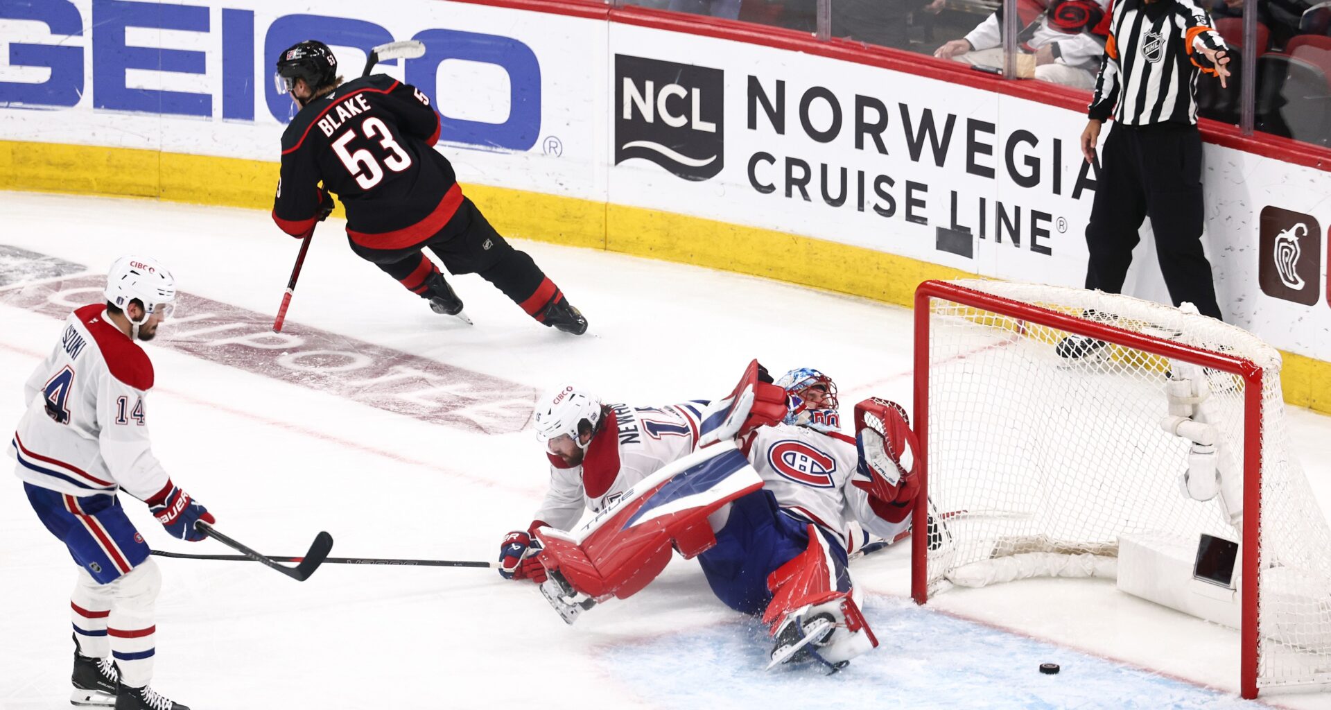 Hockey player scores a goal past a goalie sprawled on his back.