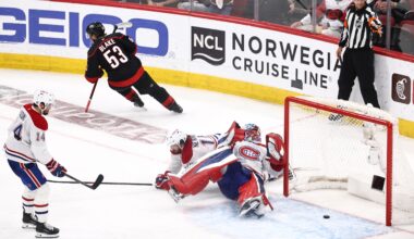 Hockey player scores a goal past a goalie sprawled on his back.