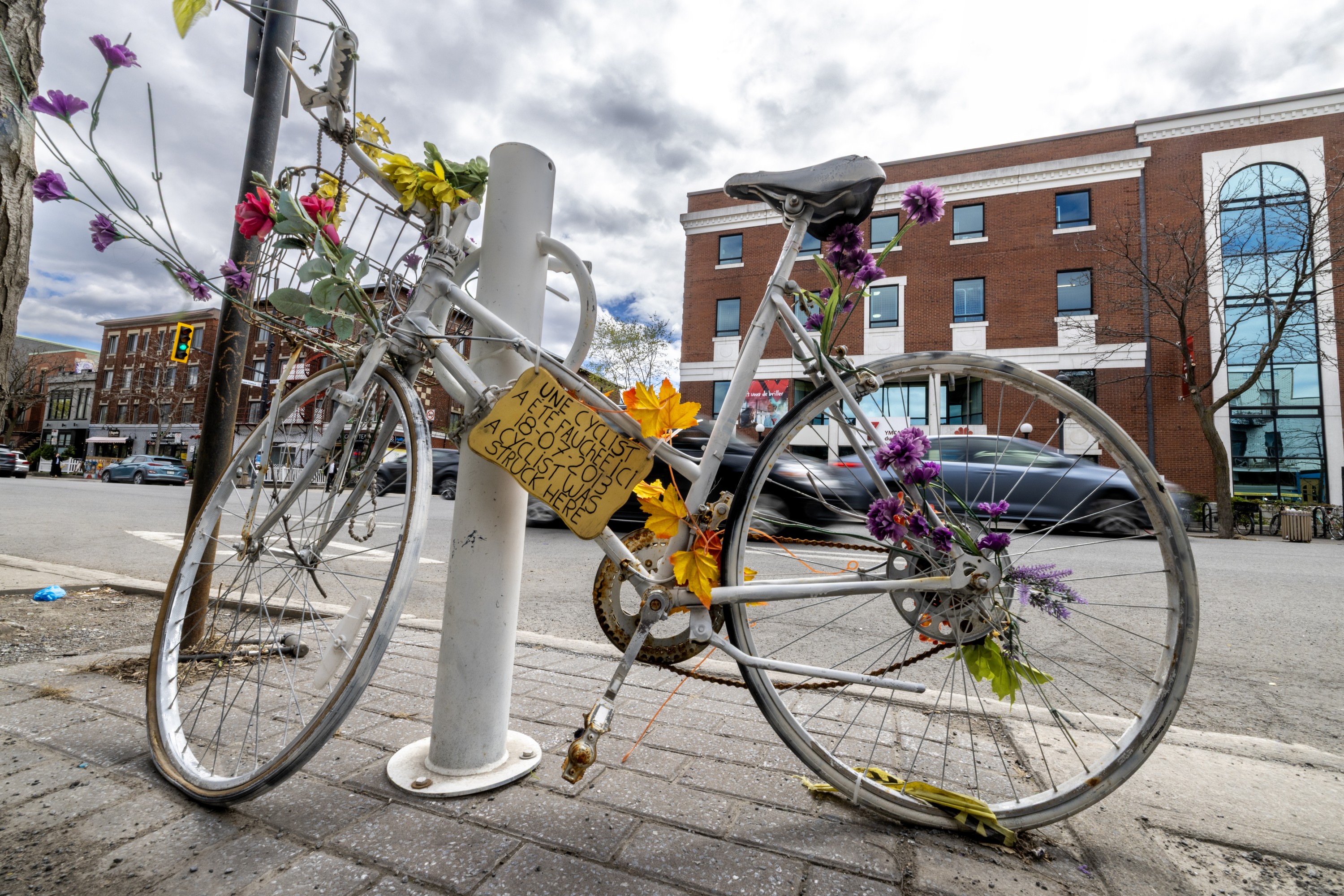 Ghost bike parked against a post on street.