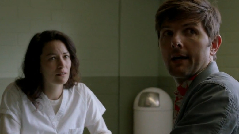 Britt Lower as Claire sitting across from Adam Scott as Max in prison in Ghosted