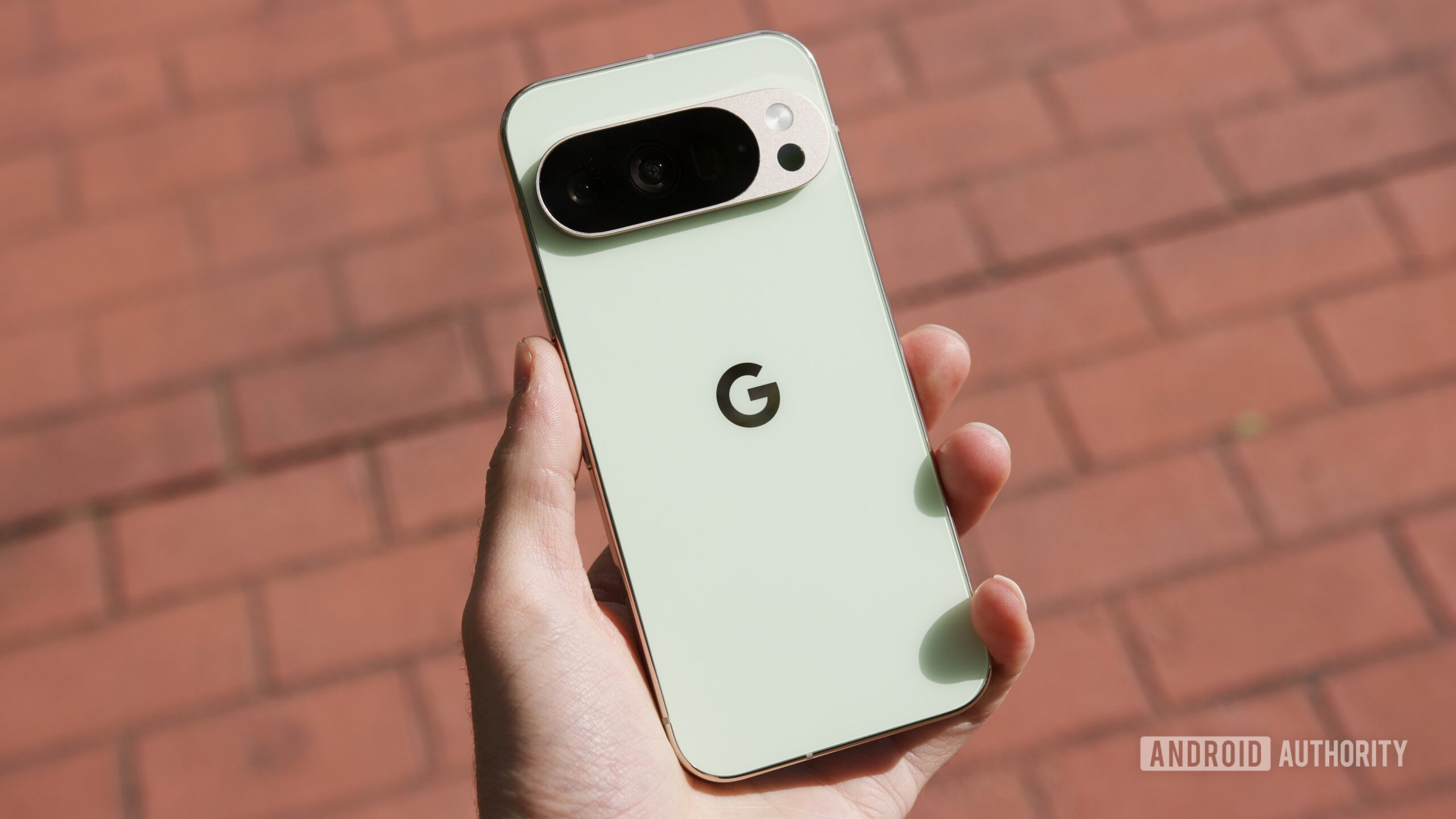Someone holding the Google Pixel 10 Pro, with a brick sidewalk behind it.