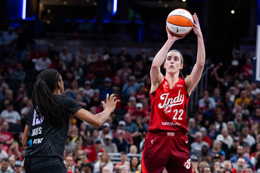 Caitlin Clark shoots the ball while Tiffany Hayes defends.