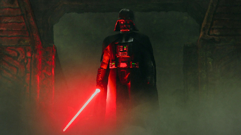 Darth Vader emerges from the shadows, wielding his red lightsaber