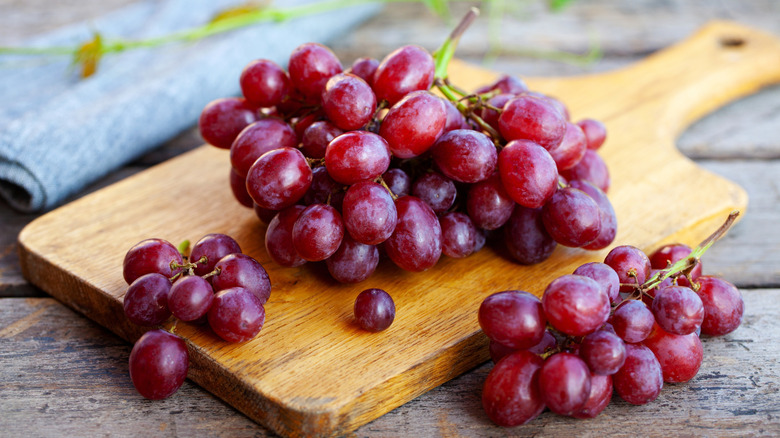 Red grapes on wooden cutting board