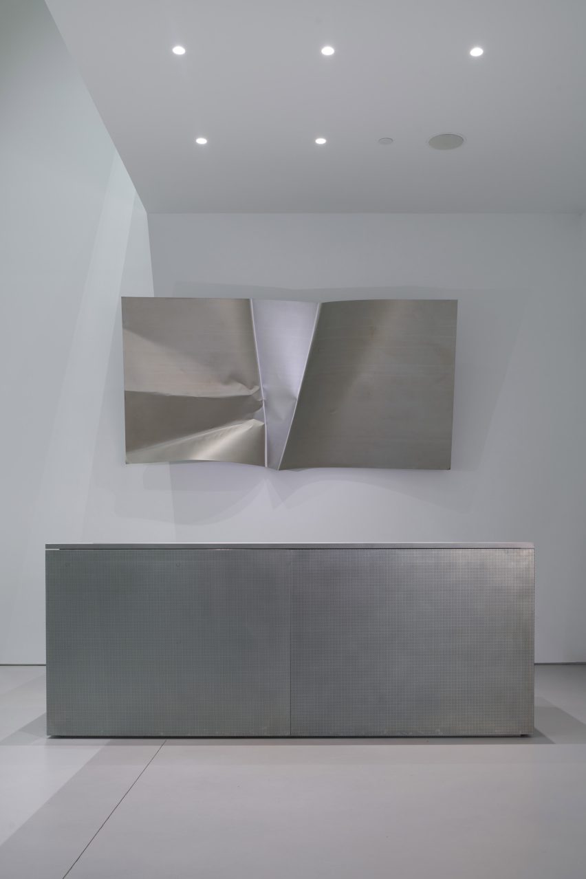 Folded titanium sheet displayed above a minimalist aluminium service counter