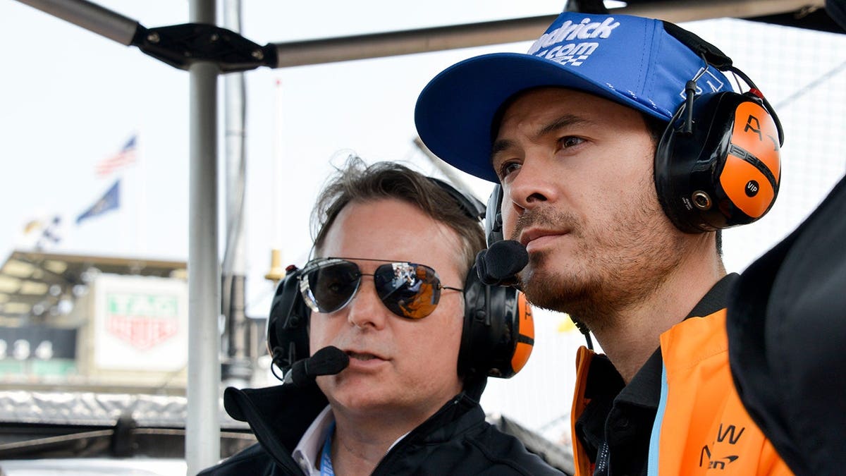 Jeff Gordon and Kyle Larson sitting in the Arrow McLaren pit box at Indianapolis Motor Speedway.